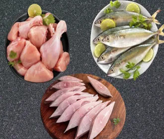 Chicken curry cut, whole mackerel with lime and sliced black pomfret laid out on a dark board