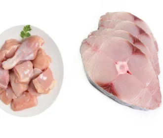Plate of chicken curry cut pieces beside a stack of king fish slices