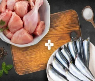 Bowl of chicken curry cut on a wooden board next to a plate of cleaned big sardines